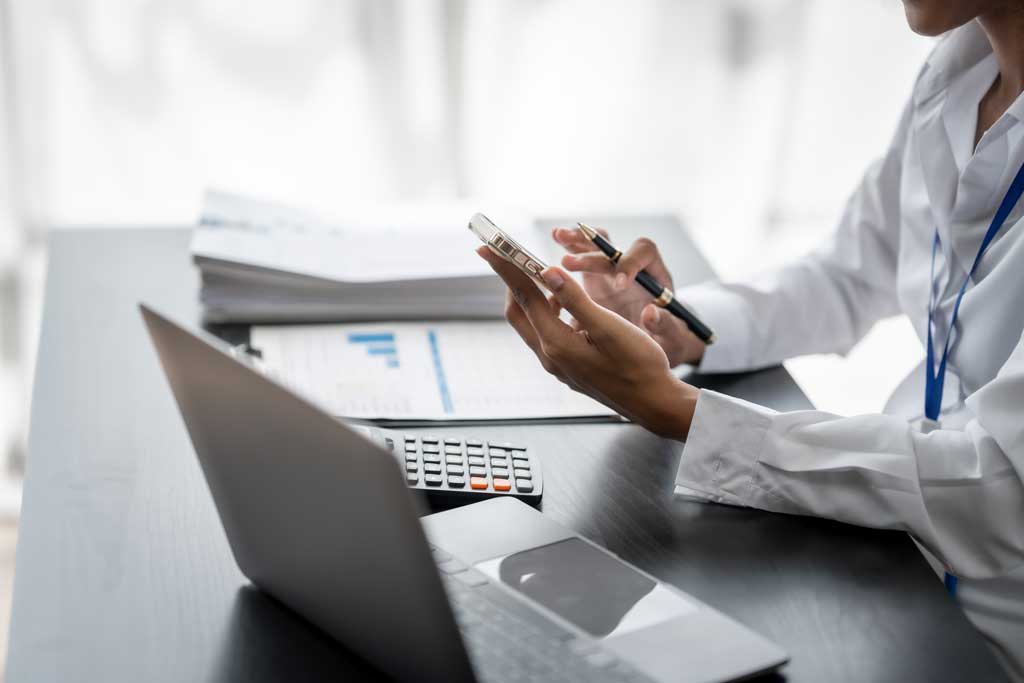 Online-Kalkulation von Laserteilen am Arbeitsplatz: Taschenrechner und Unterlagen neben dem Rechner – mit dem Sofortpreis-Kalkulator entfällt das manuelle Angebotsrechnen